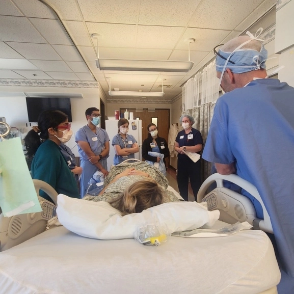 OBGYN faculty and residents discuss a patient's care at her bedside.