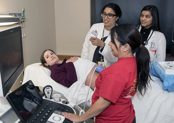 OBGYN fellows review a patient's sonogram in a hospital room.