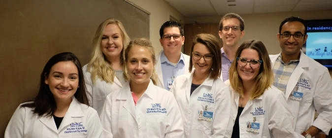 OBGYN residents and faculty pose for a photo in the white coats.