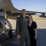 Portrait of Kristian Ramage, OBGYN resident, with her partner in front of an Airforce fighter plane.