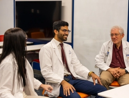 Medical students sitting with an instructor around a classroom table.