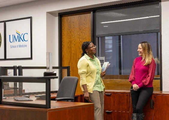 A School of Medicine faculty/staff member listens intently to his colleague as she speaks.