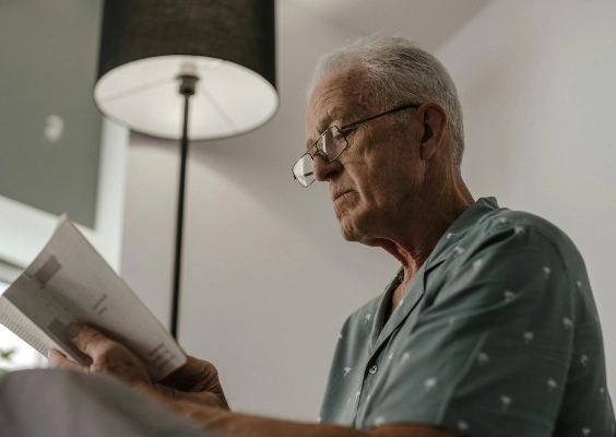 An older man using glasses to read a book.