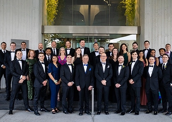 Orthopaedic surgery residents and faculty pose for a group photo while dressed in their formal wear at a group event.