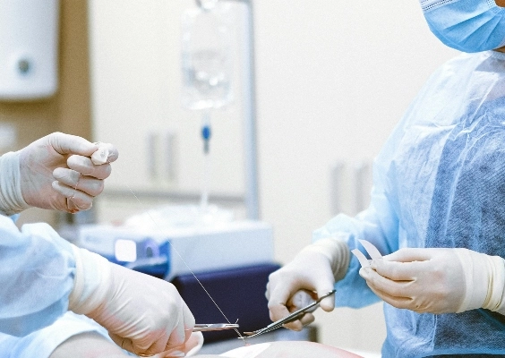 Close up of two surgeons hands as they sew a patient up after surgery.