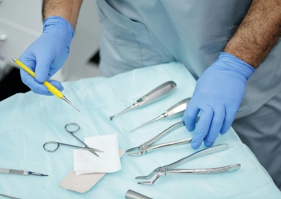 Close up of a surgeons hands as they select surgical tools from a cart in the operating room.