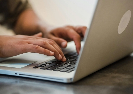 Close up of a person's hands as they type on the computer.