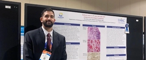 A pathology resident standing in front of her research poster at the Health Sciences Research Summit. 