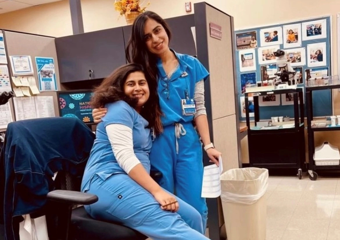 Two pathology residents side by side smiling at their hospital station. 