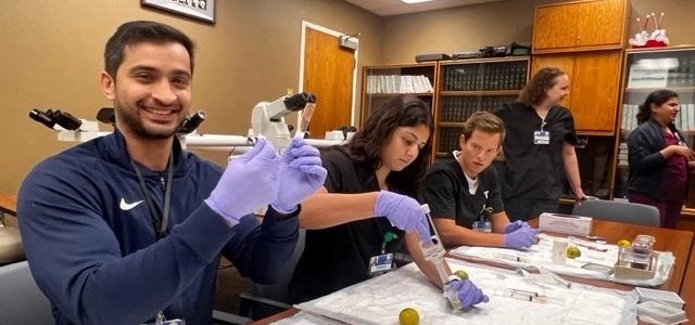 Two pathology residents smiling while working at their station in the hospital. 