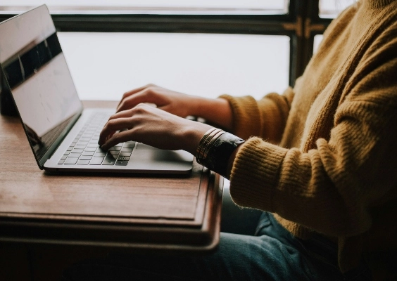 Closeup of a person's hands as they type on a computer at their desk.