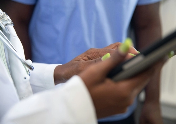 Closeup of doctors hands reviewing information with a patient on their tablet. 