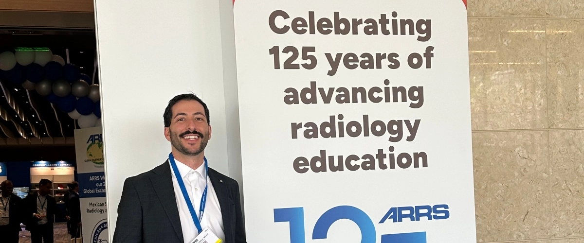 Dr. and resident, Joseph Ayoub standing outside of the 2025 RSNA Conference, which he presented at.