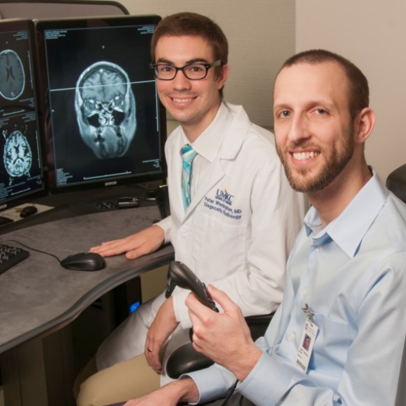 Two people sit together in front of a computer with x-rays