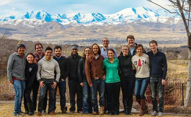 A group of people stand in front of a mountain.