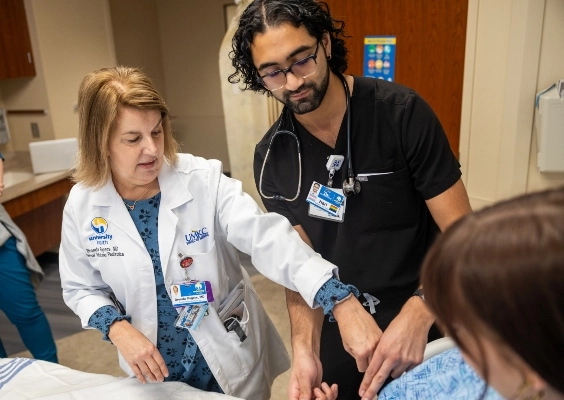 Student in black scrubs and mentor in white jacket in clinical type setting