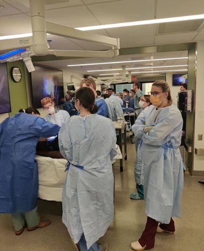 Students wearing scrubs surround hospital beds