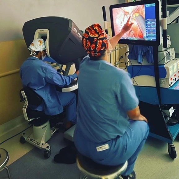 A doctor in scrubs looks at a screen while another looks into a medical device