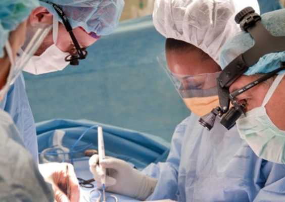 Three doctors in blue scrubs focus downward