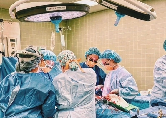 Group in scrubs surround surgical table