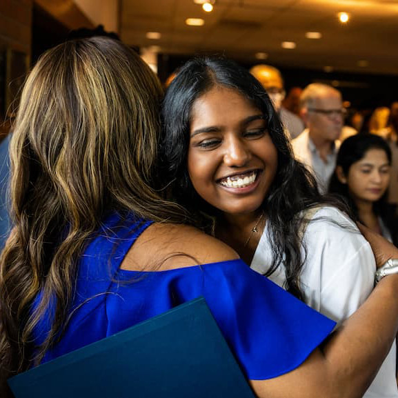 To M.D. program graduates hug during match day as they find out which residency program they've matched with.