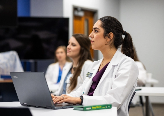 Medical students listen to a class lecture while taking notes.