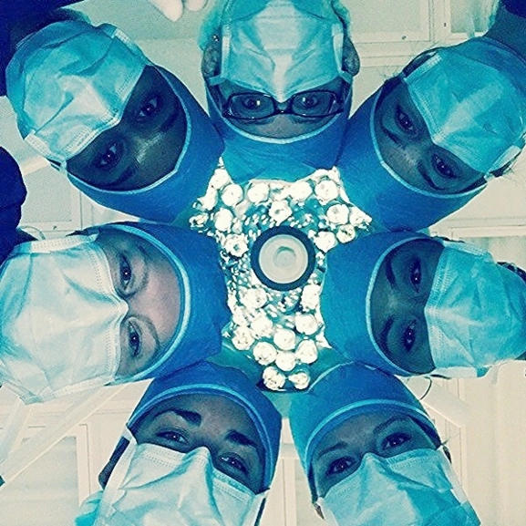 Looking up the faces of a group of orthopaedic surgeons in an operating room.