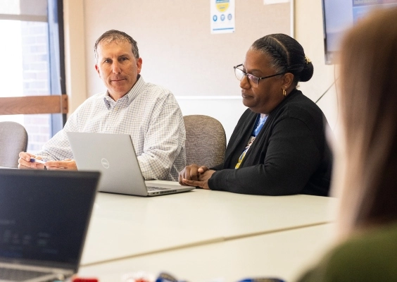 Staff from the Office of Research Administration sit conversing around a conference table.