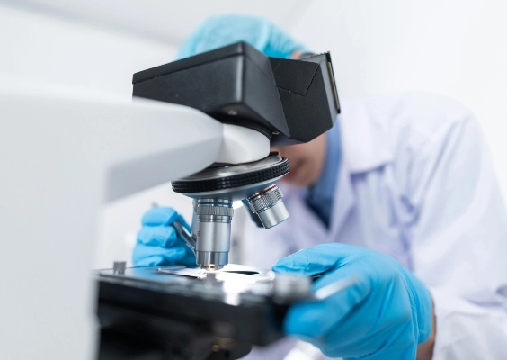 A medical researcher looks through a microscope.