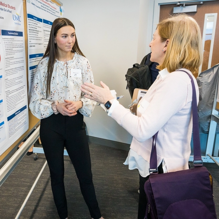 A students talks with a faculty member about their research at the Health Sciences Research Summit.