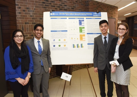 School of Medicine students stand in front of their research presentation poster.