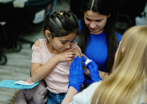 A medical student providing care to a young child at a community healthcare event.